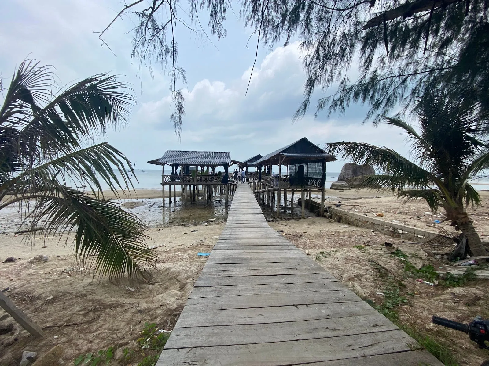 A wooden walkway across the sand to a stilt seafood restaurant at Cay Sao