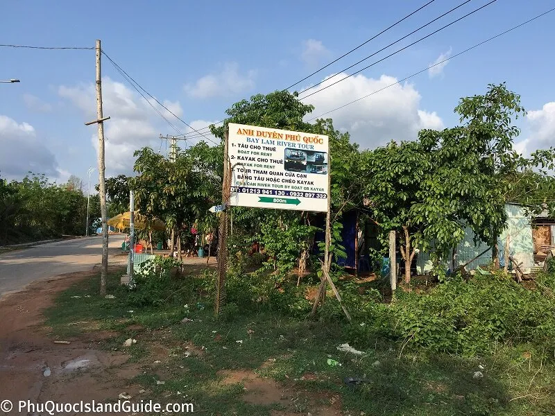 Roadside billboard advertising Cua Can river tours by boat or kayak, with an arrow pointing 800 m down the road
