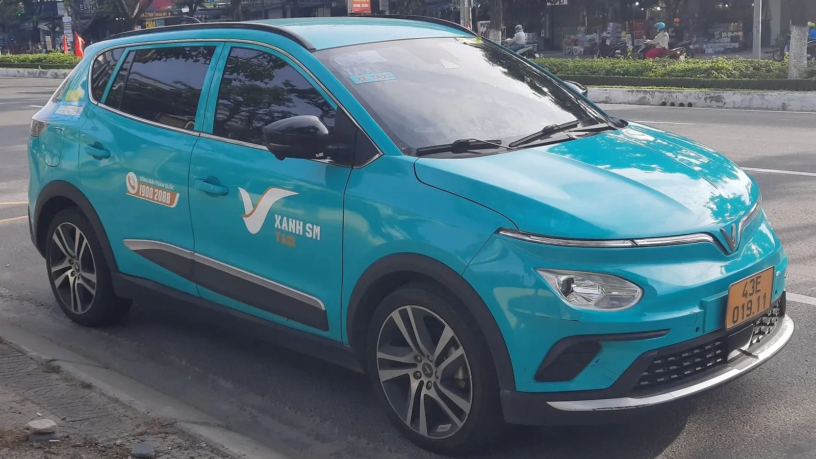 A green Xanh SM electric taxi parked at the roadside