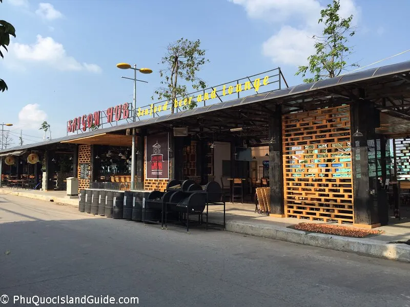 Street view of Saigon Hub, an open-fronted bar and lounge with a yellow and red sign, timber pallet screens and outdoor seating